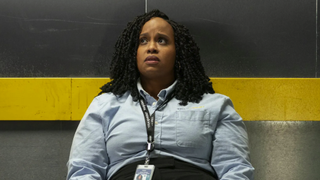 How To Die Alone creator and star Natasha Rothwell, slumped on a bench and wearing blue airport uniform, plays a 35-year-old woman working a dead-end job at JFK